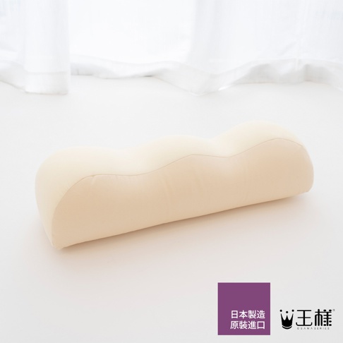 一個奶油色、人體工學設計的抬腿枕，表面有波浪狀曲線，材質看起來像柔軟的織物。