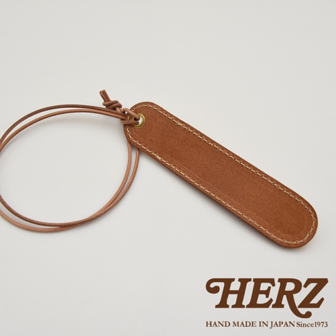 HERZ 品牌標誌，下方有 HAND MADE IN JAPAN Since1973 字樣，旁邊是棕色皮革製成的筆套，附有細長皮繩。