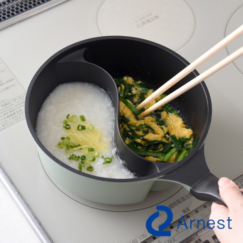 一個雙鍋，一邊是米粥，另一邊是炒蛋和蔥，用筷子將其攪拌