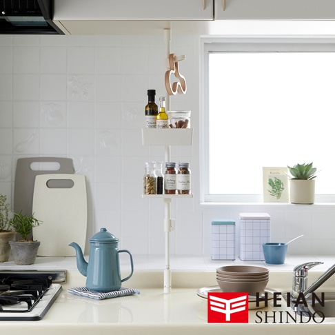 白色伸縮桿直撐架，附有兩個白色層架，上方層架擺放著玻璃瓶裝的香料、橄欖油和調味料，下方層架擺放著三瓶香料，架子上方有兩個木製掛勾。