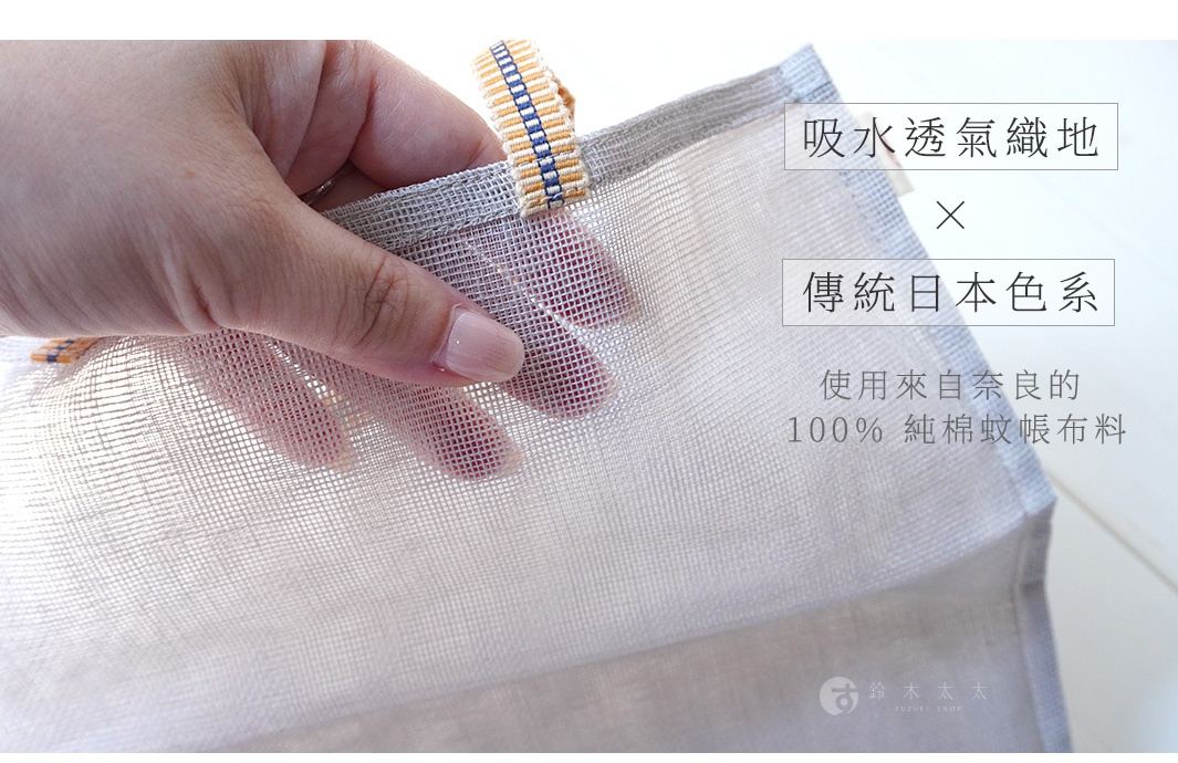 手持淺灰色網狀提把蔬果收納袋，袋身材質為透氣純棉紗布，提把飾有黃藍色編織紋路。