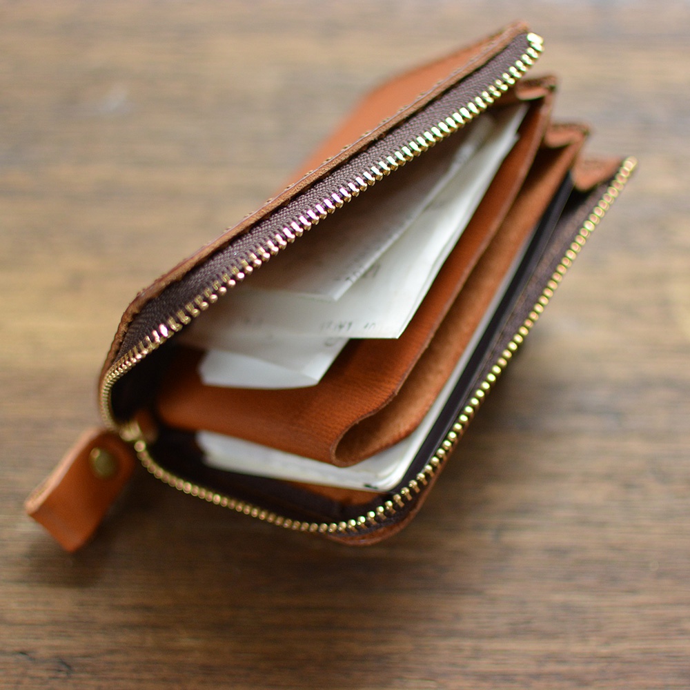 職人手作皮革Organ口袋拉鍊短夾 GS-32，展示皮革的自然紋理和溫潤的棕色調，拉鍊部分採用金色金屬，內部收納了多張票據，整體呈現簡約實用的設計。