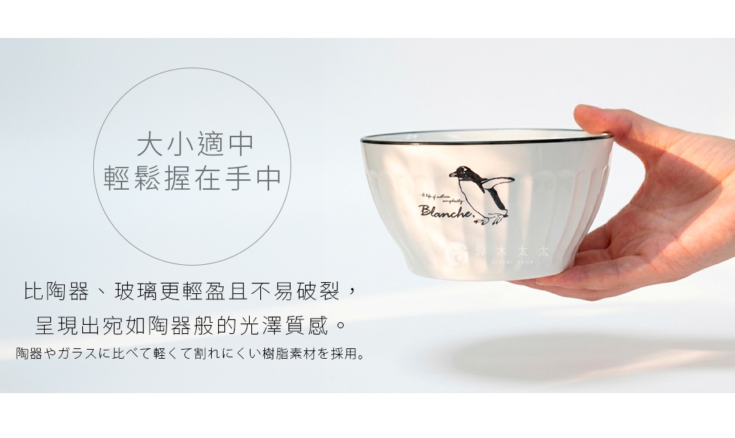 手持一個印有企鵝圖案的白色輕量樹脂餐碗，碗身帶有豎條紋設計與黑色包邊，呈現簡約日系質感，圖片配有說明文字強調該碗輕巧耐摔且質感優良，適合作為居家餐具使用。