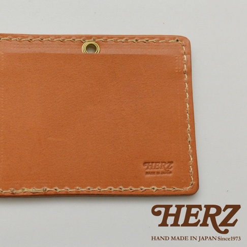 淺棕色皮革橫式證件夾，採用手工縫線，正面右下角有「HERZ」品牌壓紋，上方有金屬掛環。