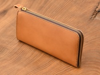 職人手作的淺棕色皮革L型長夾，採用雙拉鍊設計，搭配金色拉鍊和皮革拉頭，縫線精緻，材質為天然皮革，質感溫潤。