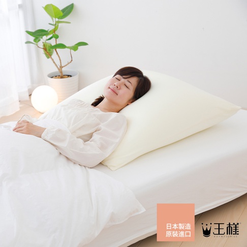 一位女性仰躺在床上，頭部枕在一個奶油色的大型枕頭上，枕頭套材質柔軟，枕頭尺寸寬大，能支撐整顆頭部。