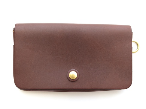 深棕色皮革製成的長夾，正面有一個黃銅色按扣，右側邊緣有一個黃銅色 D 型環。