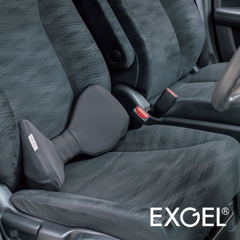 黑色汽車用腰墊，採用柔軟布料材質，設計成符合人體工學的弓形，提供腰部支撐。腰墊放置於汽車座椅上，旁邊有安全帶扣。