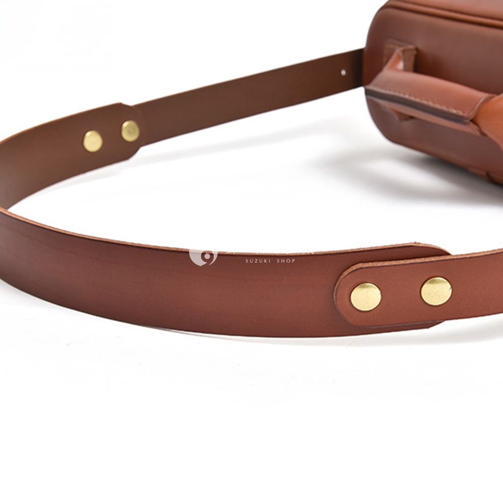Hermes 相機包的棕色皮革錶帶，配有金色釦子，上面印有「SUZUKI SHOP」字樣。