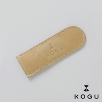淺棕色植鞣皮革製成的咖啡器具握柄隔熱套，表面壓印有 KOGU 品牌標誌，以白色縫線包邊，設計簡約。