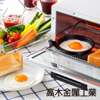 日本製烤箱內，一個黑色圓形烤盤盛著一個金黃蛋黃的煎蛋，烤箱架上擺放著烤過的吐司。盤邊有蔬菜拼盤，包含小番茄、綠花椰、黃甜椒、紅蘿蔔、蘆筍和黃瓜。