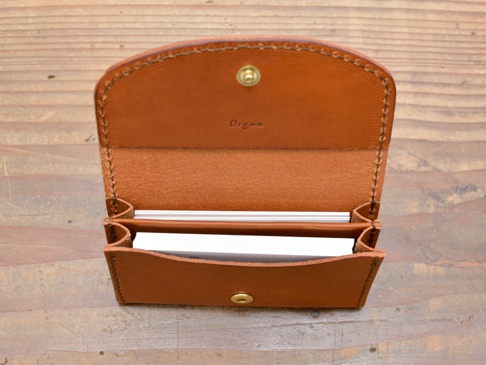 職人手作棕色皮革Organ商務名片夾，打開狀態，可見內部空間及部分名片，皮革表面有自然紋理，邊緣縫線清晰。