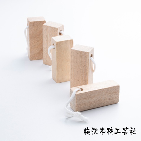 五個淺色木製長方體狀的樟木條，部分帶有白色棉繩穿過頂部的小孔，排成斜線，背景為白色。