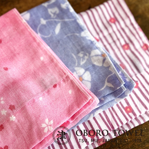 津OBORO 朧染和紋款待之心紗布毛巾，粉色、藍色和條紋圖案，底部有品牌logo和產地資訊