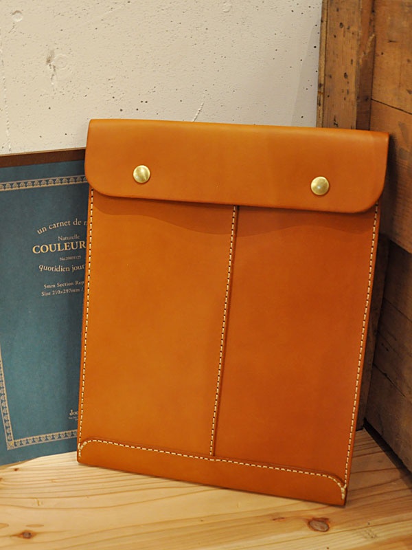 職人手作皮革信封式雙釦手拿袋，採用溫潤的棕褐色皮革，搭配金屬雙釦，整體設計簡潔，車縫線清晰。