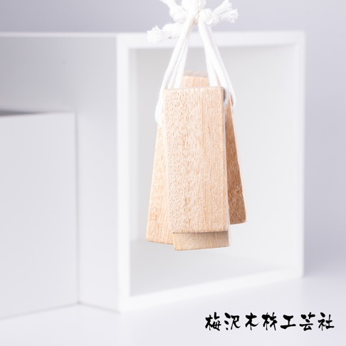 數塊淺棕色、紋理明顯的天然樟木條，以白色繩索串起懸掛，背景為白色方框。