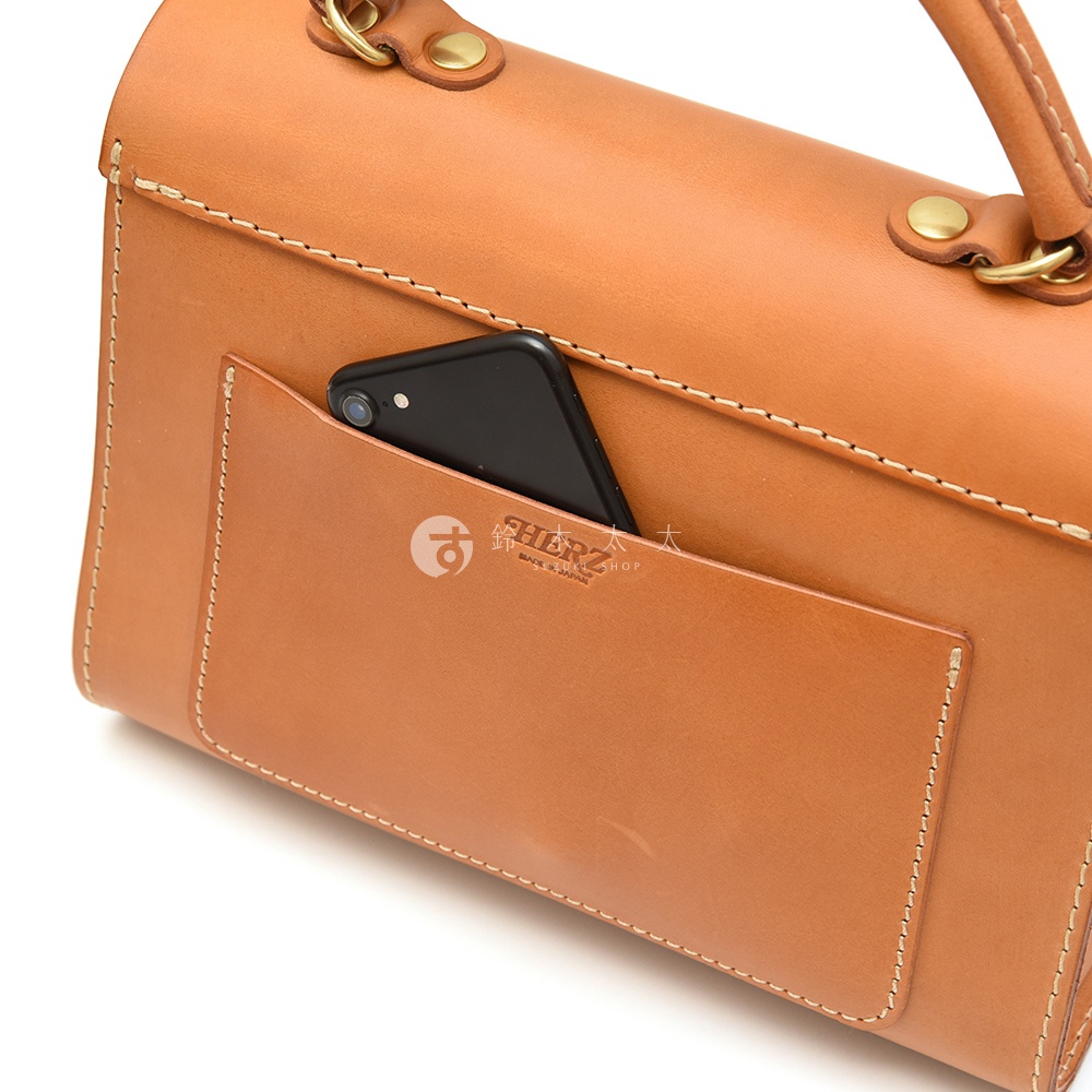 一個棕色皮革手提包，側面有一個用於放置手機的外部口袋，上面印有 HERZ 的標誌。