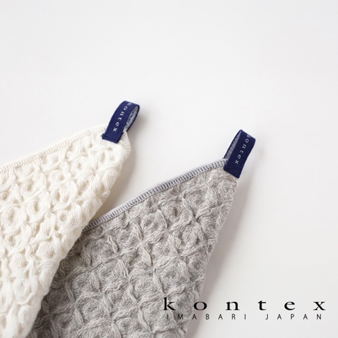 兩條棉麻混紡方巾，一條為白色，另一條為淺灰色，皆有鬆餅紋路，頂部有深藍色品牌標籤。