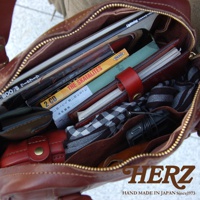 職人手作皮革迷你波士頓包，深棕色水洗加工皮革，內有書籍、CD、筆記本、耳機及格子布料，拉鍊開口。