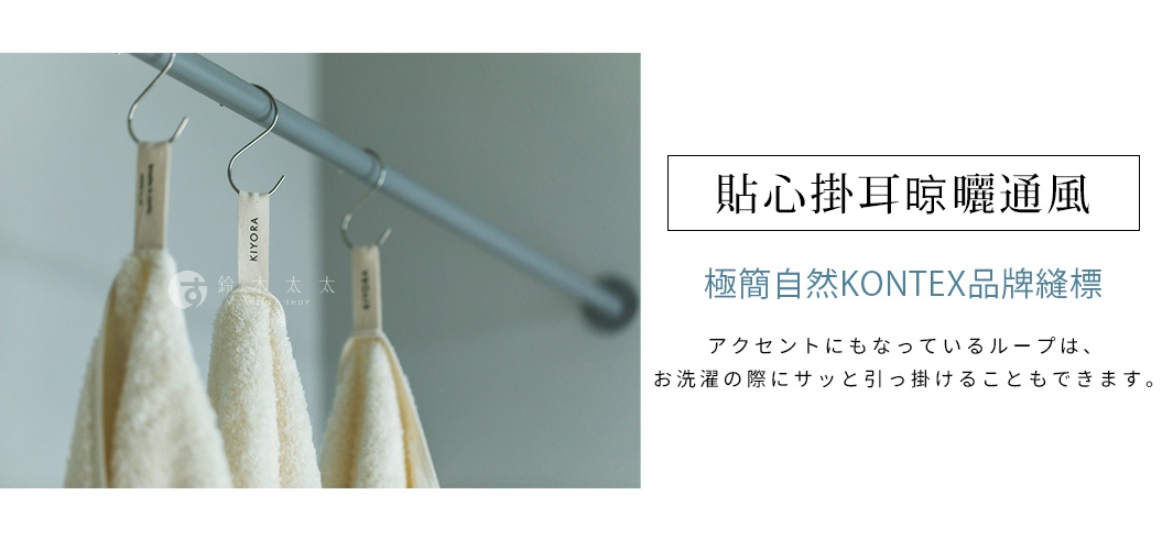 三條米白色毛巾懸掛在金屬桿上，毛巾上方設有縫製的淺色掛環標籤，標籤上印有品牌名稱，此設計方便毛巾懸掛通風晾曬。