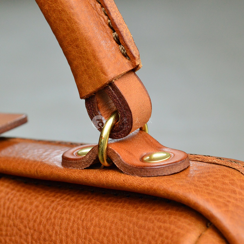 職人手作皮革Organ方形口金托特包G-55，特寫展示包款的皮革提把與金屬釦件細節，皮革呈現天然紋理與溫潤光澤，金屬釦件為復古金色。