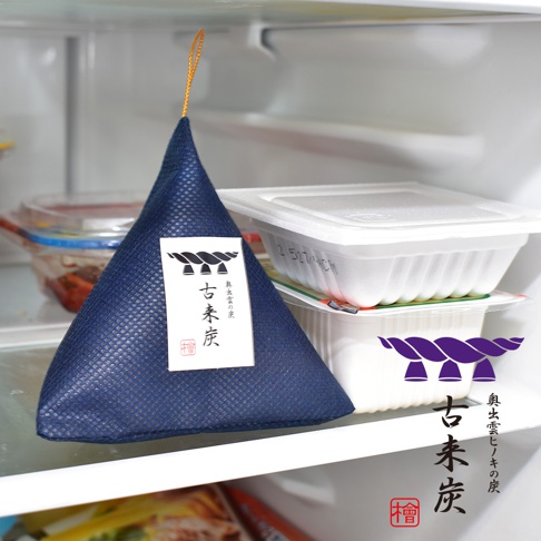 藍色網格紋立體三角包裝，內含古來炭，頂部有黃色掛繩，標籤上有黑色中文「古來炭」字樣及日文說明，置於冰箱內。