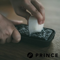 一雙手正在使用黑色兩用盒上的磨泥器，將白色塊狀物磨成細碎狀，盒內已有多量磨碎的細末。