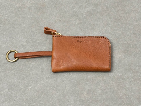 職人手作皮革Organ抽繩鑰匙包，焦糖棕色，採用柔軟的皮革材質，配有金色拉鍊、皮革拉環和金屬鑰匙圈。