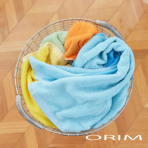 金屬籃中裝有四色（黃色、淺綠色、橘色、藍色）的 HARUKA 今治浴巾，浴巾質地柔軟，呈現堆疊的狀態。