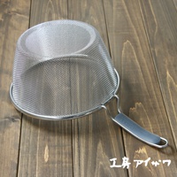 不鏽鋼濾網，網目細緻，搭配灰色矽膠握柄，整體呈銀色，置於木紋桌面。