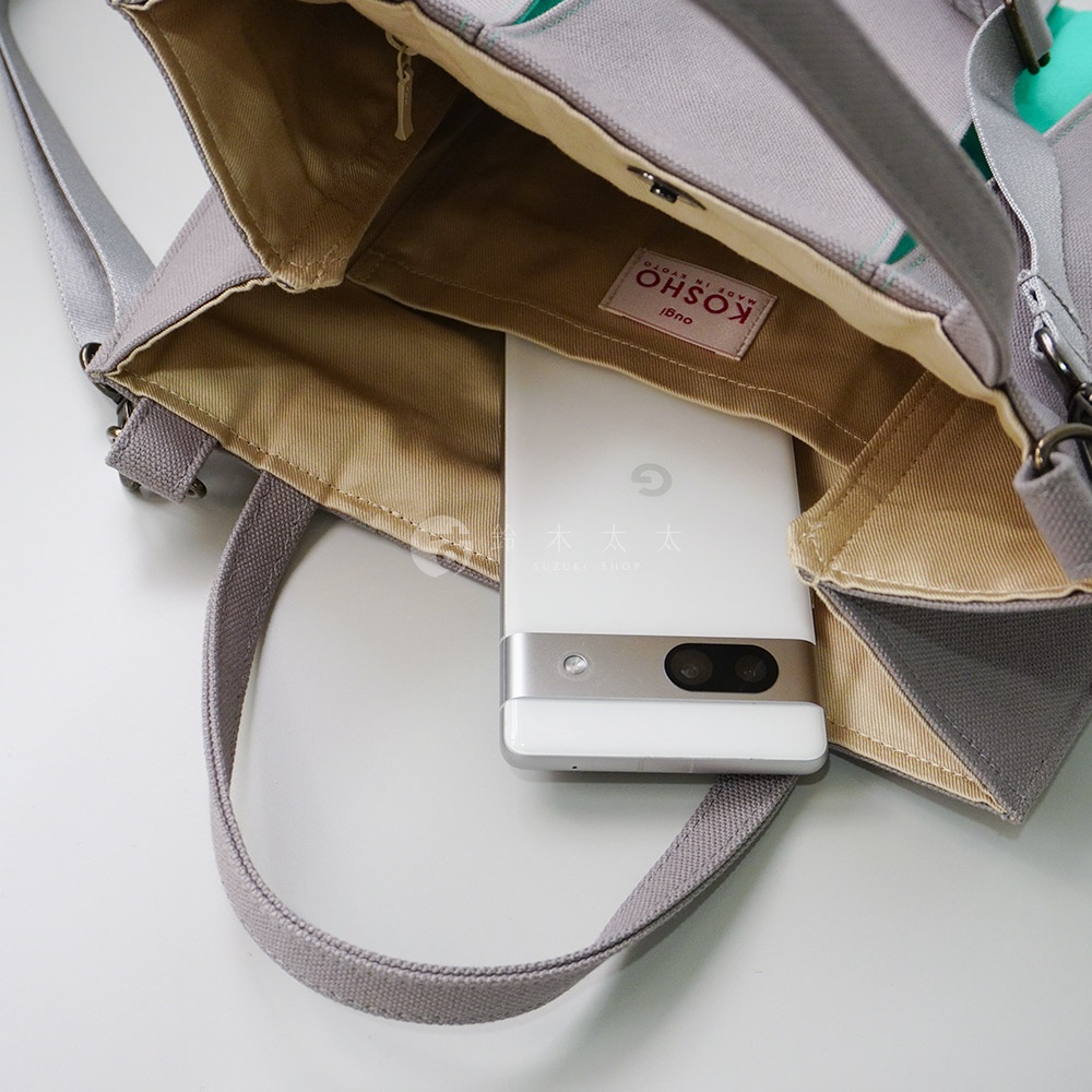 京都職人手作ougi棉帆布兩用扇形托特包，灰色帆布材質，內裡為卡其色。包包內有一個白色手機，顯示品牌標籤。