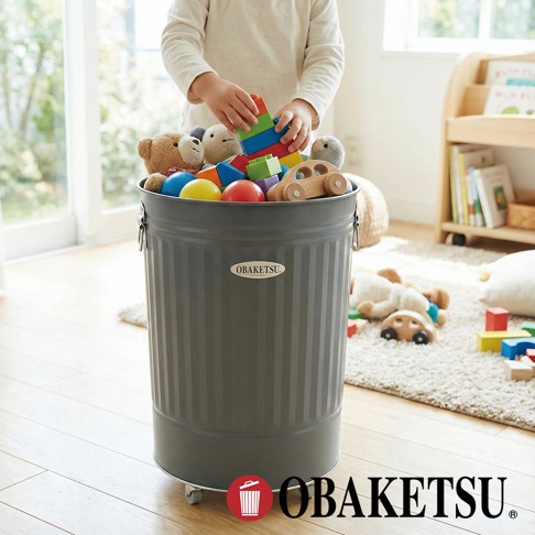 OBAKETSU 經典復古風附輪玩具收納桶，裝滿各式彩色玩具，由一位小孩正將積木放入桶中。