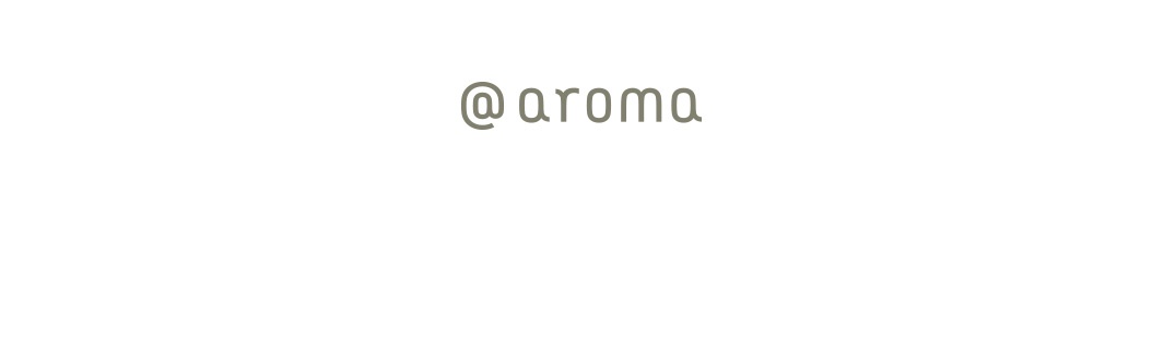 白色背景上，圓形符號「@」後跟隨「aroma」字樣，字體為淺綠色。
