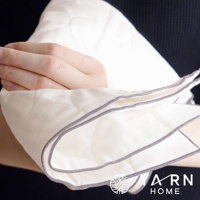 一雙手正拿著一塊米白色、帶有菱形絎縫紋路的廚房拭巾，拭巾邊緣滾有灰色包邊，質地柔軟。