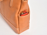 職人手作皮革直式肩背托特包 (T-32-T)，淺棕色皮革，側邊置物袋裝有紅色零錢包，縫線清晰。