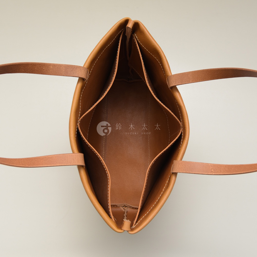 職人手作皮革托特包，呈現自然棕色，包內設有四個隔層，展現皮革的紋理與細膩車縫。