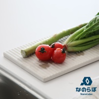 淺灰色條紋珪藻土置物墊，上面放著三顆紅色小番茄和一束綠色蔬菜。