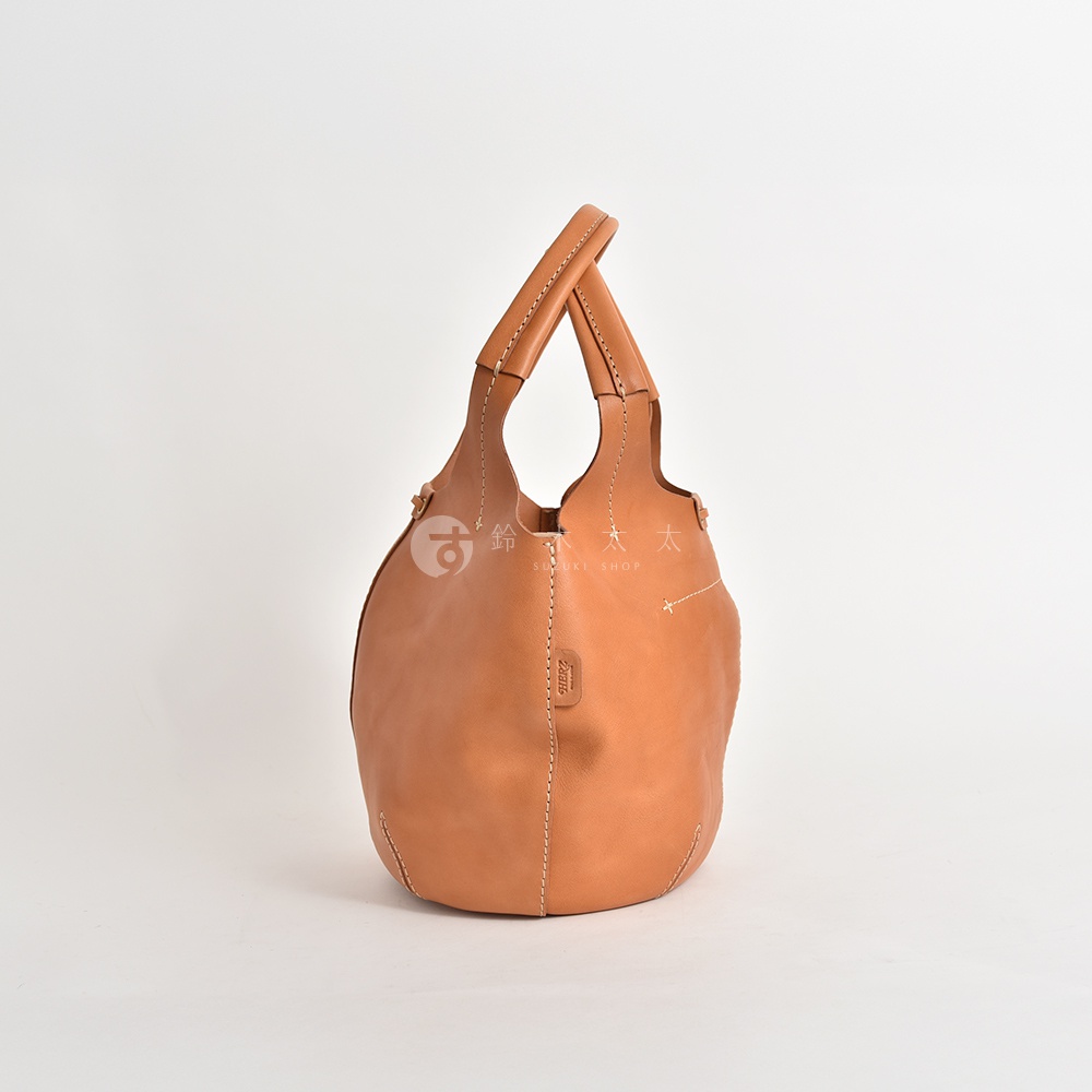 職人手作皮革球形肩掛托特包，呈現自然棕色皮革，圓潤飽滿的包身，搭配雙提把設計，車縫線清晰。