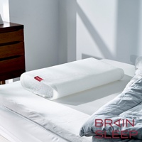 一張白色網狀材質的「腦眠科技枕」，枕面有網格紋理，一側有紅色品牌標籤。枕頭置於白色床單上，旁邊疊著灰色被子。