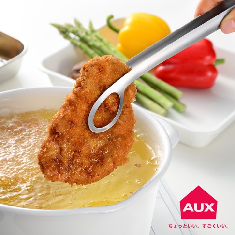 leye 靈活炸物夾，不鏽鋼材質，以夾子夾住一塊金黃酥脆的炸物，炸物正從冒泡的熱油中取出，背景有蘆筍、紅黃甜椒。