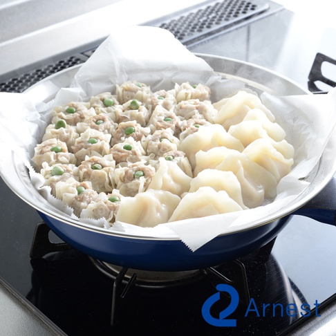 不鏽鋼蒸盤內盛放著整齊排列的燒賣和水餃，燒賣上點綴著綠色豌豆。蒸盤置於瓦斯爐上，周圍有水蒸氣。