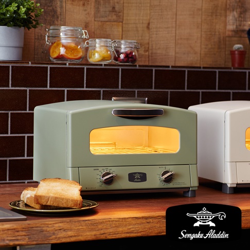 復古風格的綠色小烤箱，配有黑色把手和玻璃門。烤箱內部有加熱管和烤架，正面有兩個旋鈕和一個計時器。旁邊還有一個白色的小烤箱。
