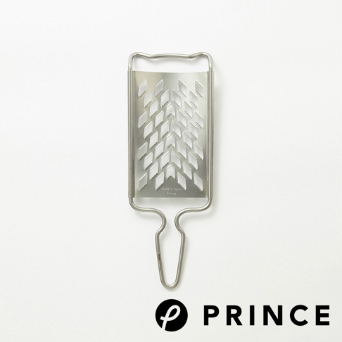 不鏽鋼製的長方形磨泥器，帶有銀色金屬光澤，表面佈滿菱形孔洞，下方有彎曲的握把，標有「Made in Japan Prince」字樣。