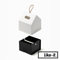 白色小屋形衛生紙盒，頂部有皮繩吊掛，側邊有長方形開口。下方為黑色方形內盒，用於放置衛生紙。