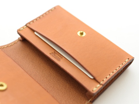 職人手作皮革名片收納夾，壓扣版 (KV-24) N，採用淺棕色牛皮製成，表面壓印品牌標誌。名片夾內層有卡槽，並以同色系縫線手工縫製，設有金色壓扣。