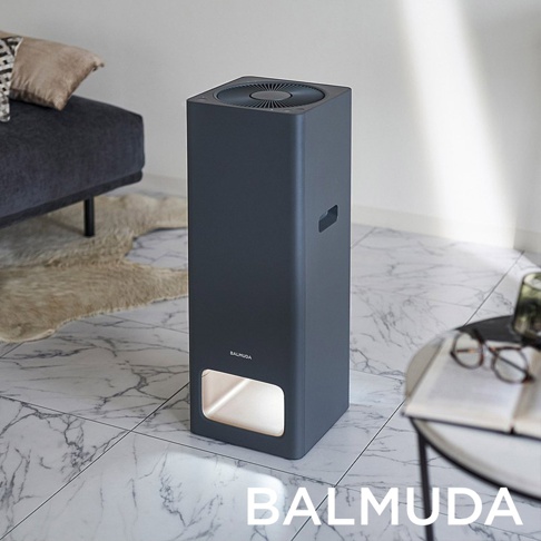 The Pure 空氣清淨機，深灰色，簡約長方體設計，頂部有圓形風扇，側面有提把，底部有長方形的發光區域，置於大理石紋地板上。