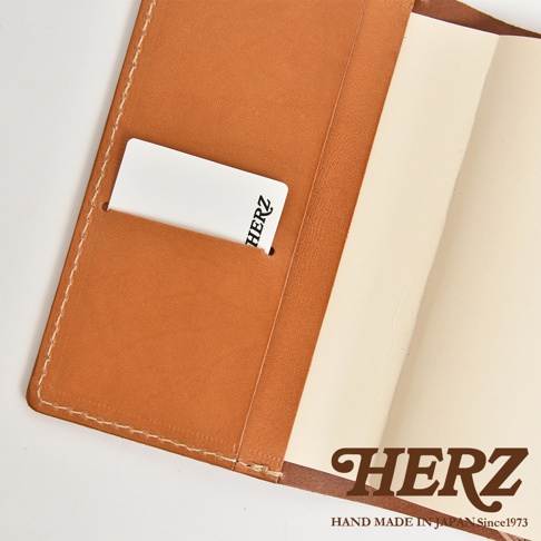 HERZ 皮革手帳書套，內有卡槽，右側為筆記本頁面，底部印有品牌標誌。