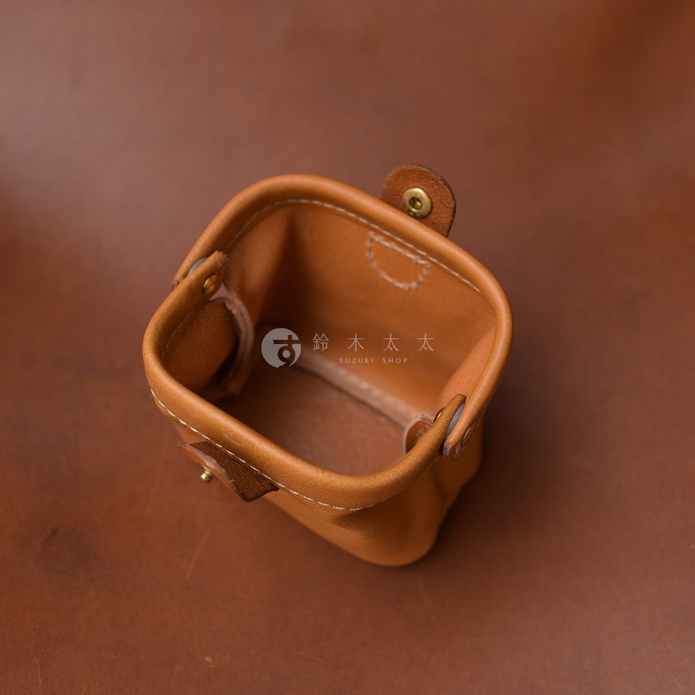 職人手作皮革口金化妝包，淺棕色皮革，方形開口，內部縫線清晰，配有黃銅色金屬釦。