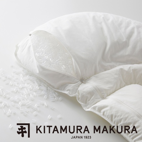 白色布質枕頭，拉鍊部分敞開，露出內部填充的許多透明小顆粒，部分顆粒散落在枕頭外。