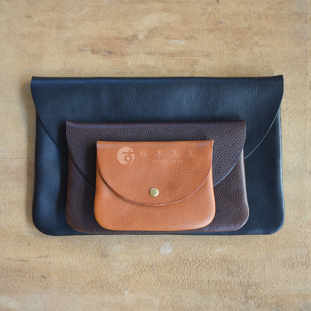三款職人手作皮革小物收納袋，依序為黑、棕、咖其色，均為鈕扣式設計，材質為皮革。